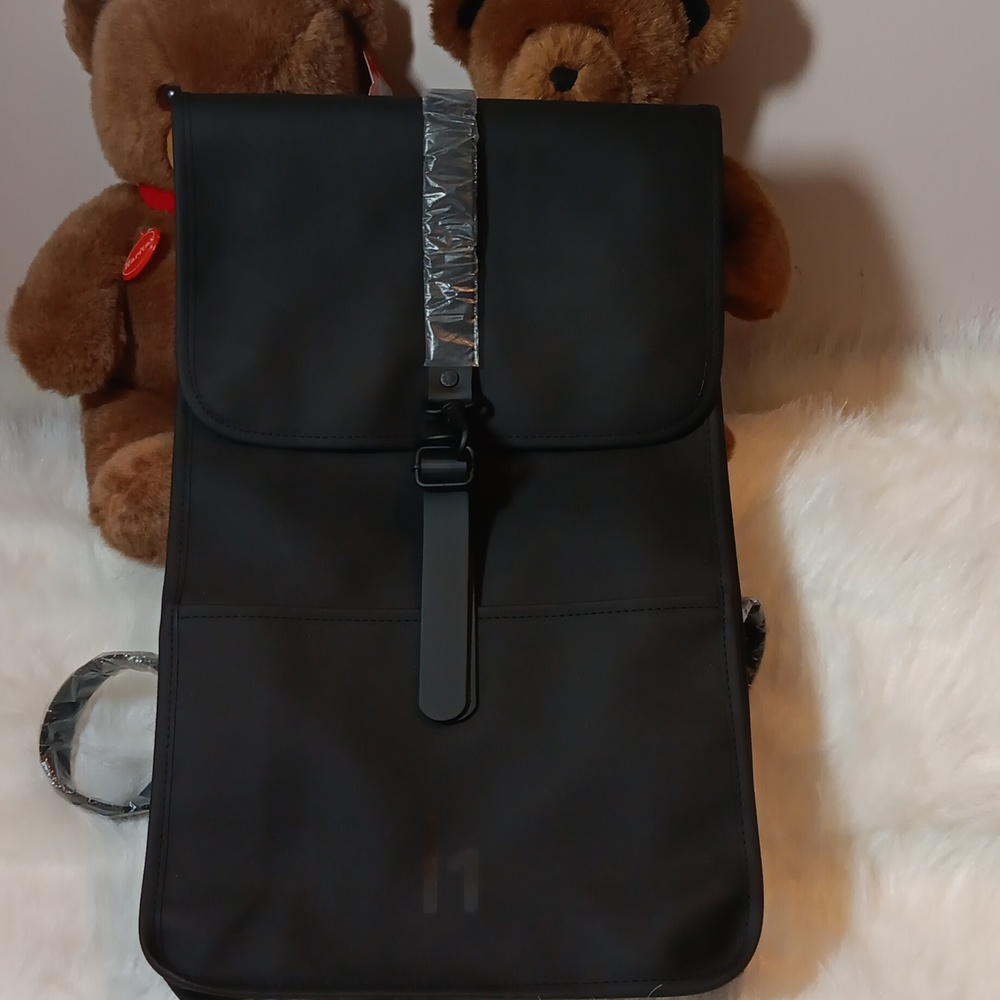 Rains, Black Silhouette Backpack Characterized by its prominent flap.
